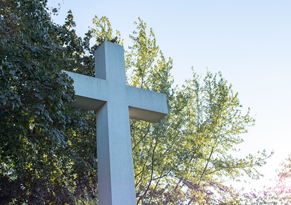 a large white cross sitting in front of a tree