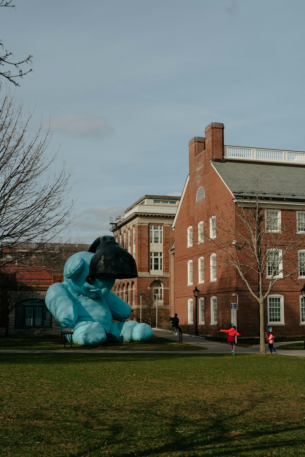 a large blue teddy bear sitting on top of a lush green field