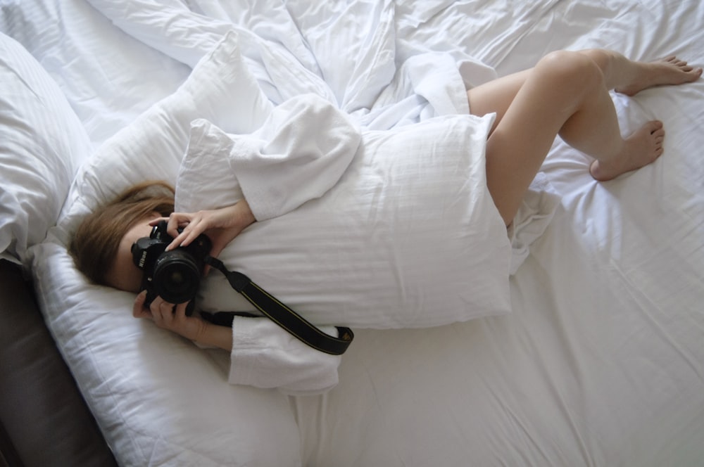a woman laying on a bed with a camera