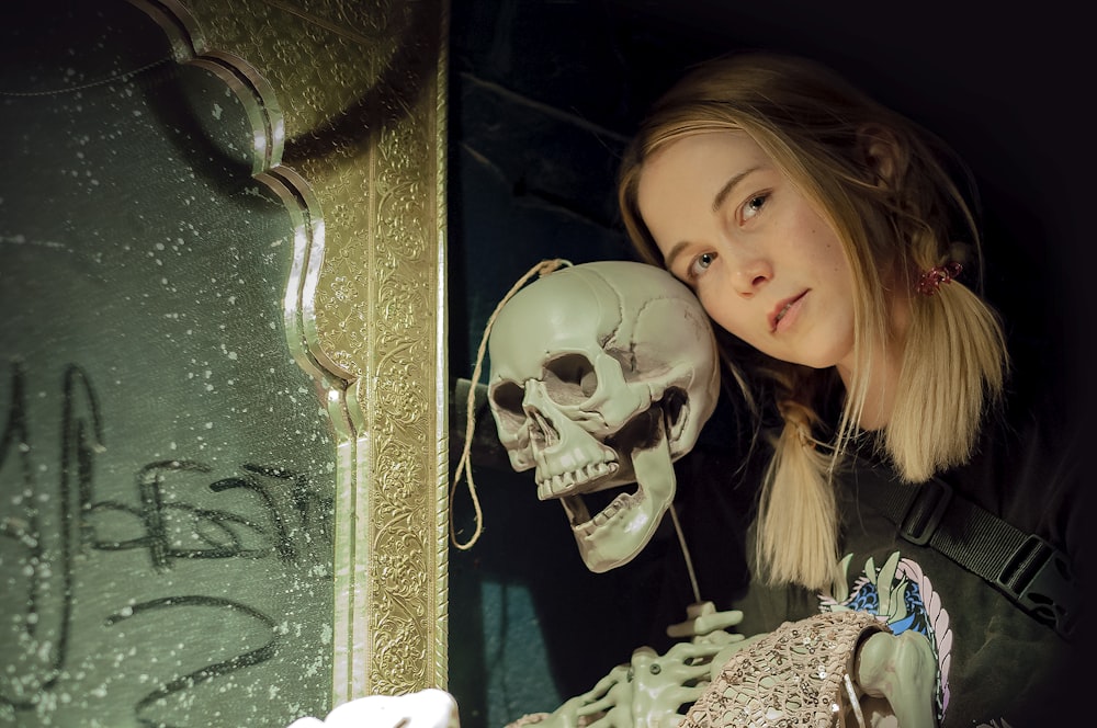 a woman holding a skull in front of a mirror