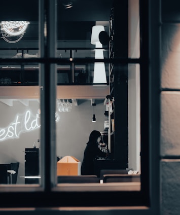 A dimly lit Tokyo bar with a mysterious woman sitting alone at the counter.