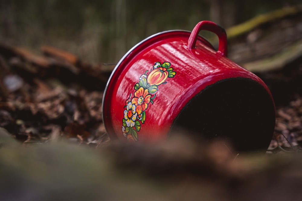 a red flower pot sitting on the ground