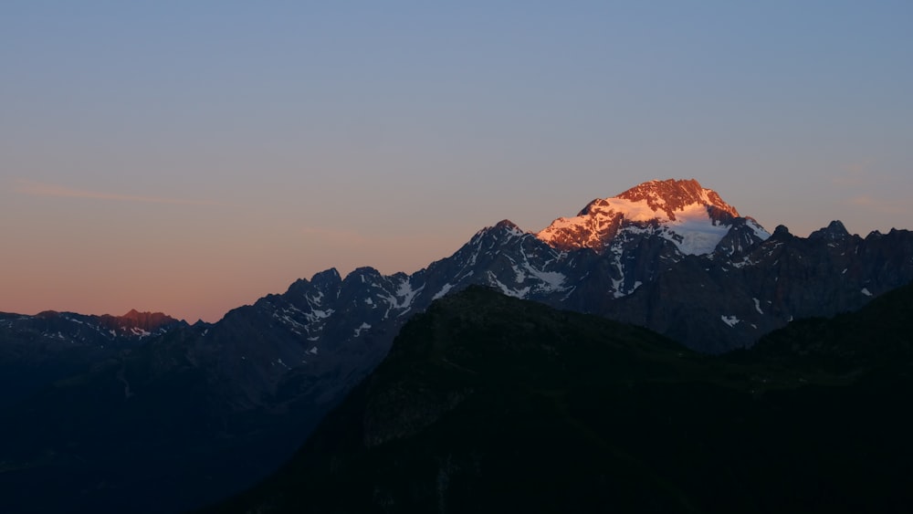 a mountain with a snow capped peak at sunset