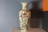 Elegant ceramic vase with delicate floral patterns displayed against a neutral background.