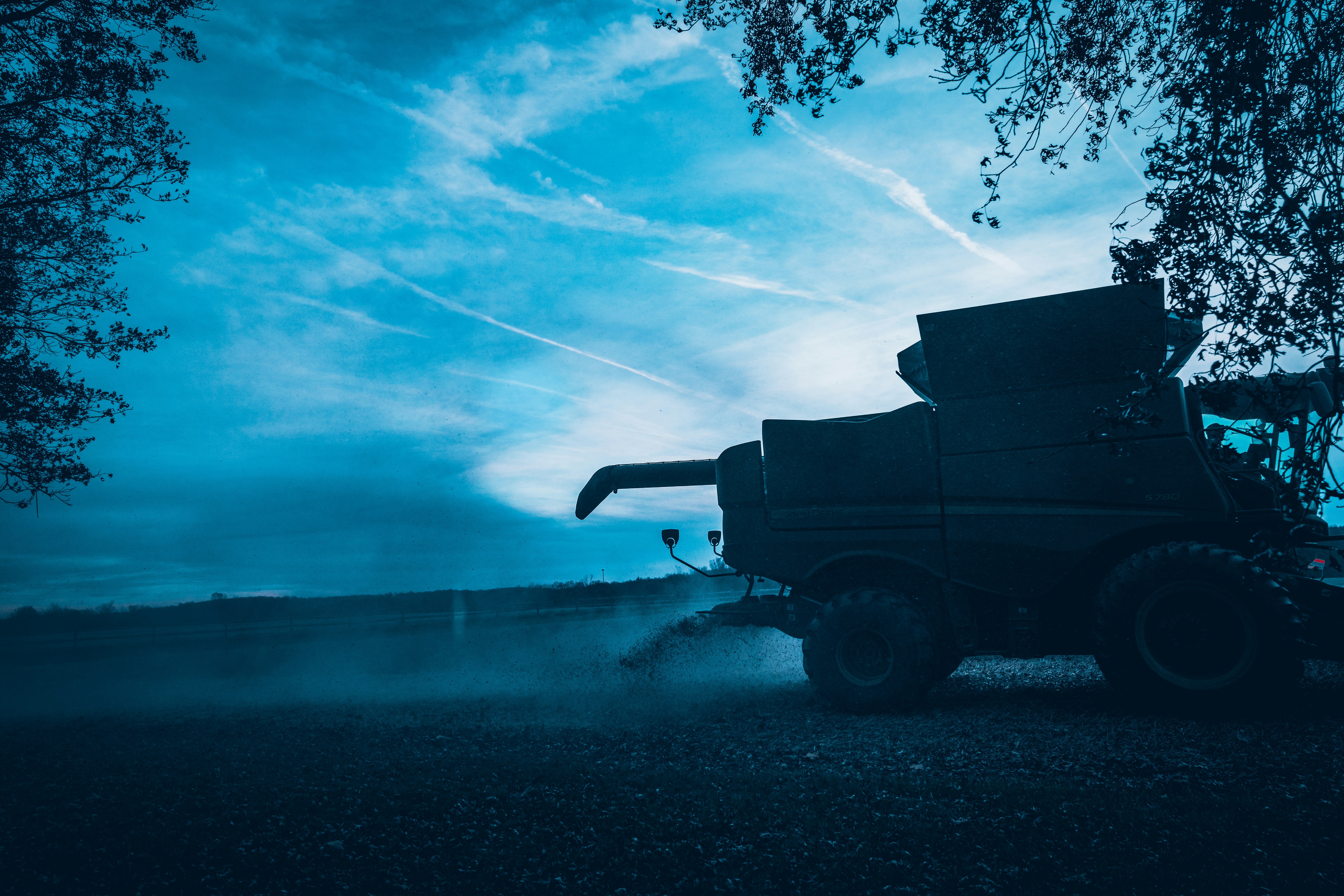 a truck driving down a dirt road under a blue sky