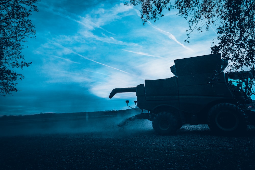 a truck driving down a dirt road under a blue sky