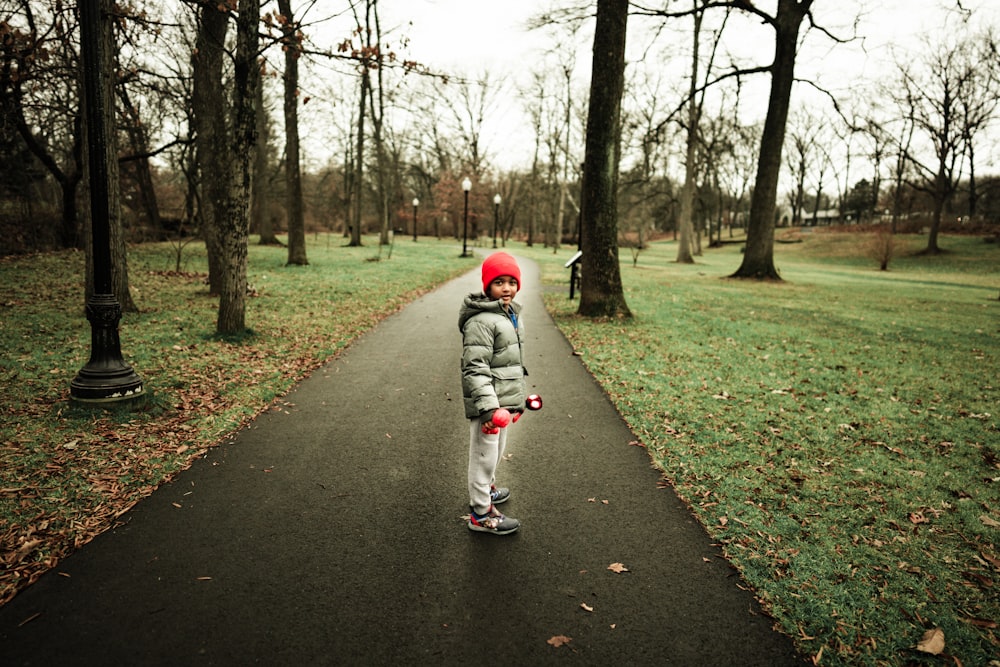 a little girl standing on a path in a park