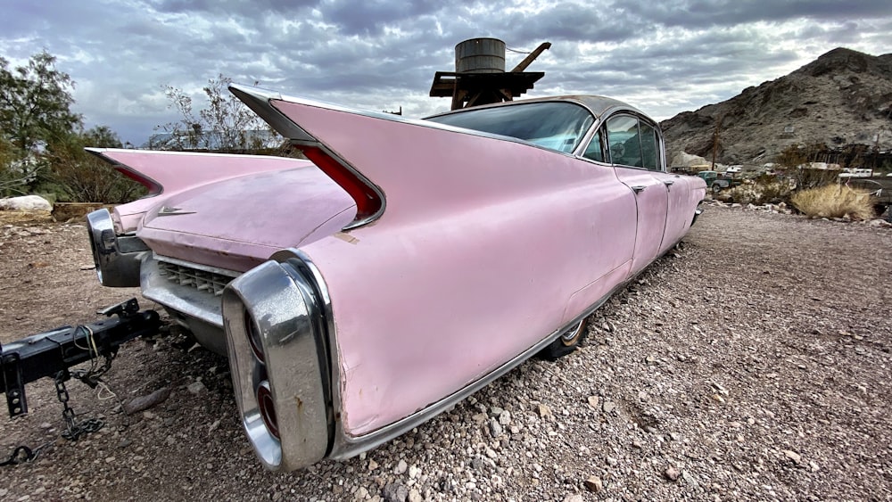 an old pink car is parked on the side of the road