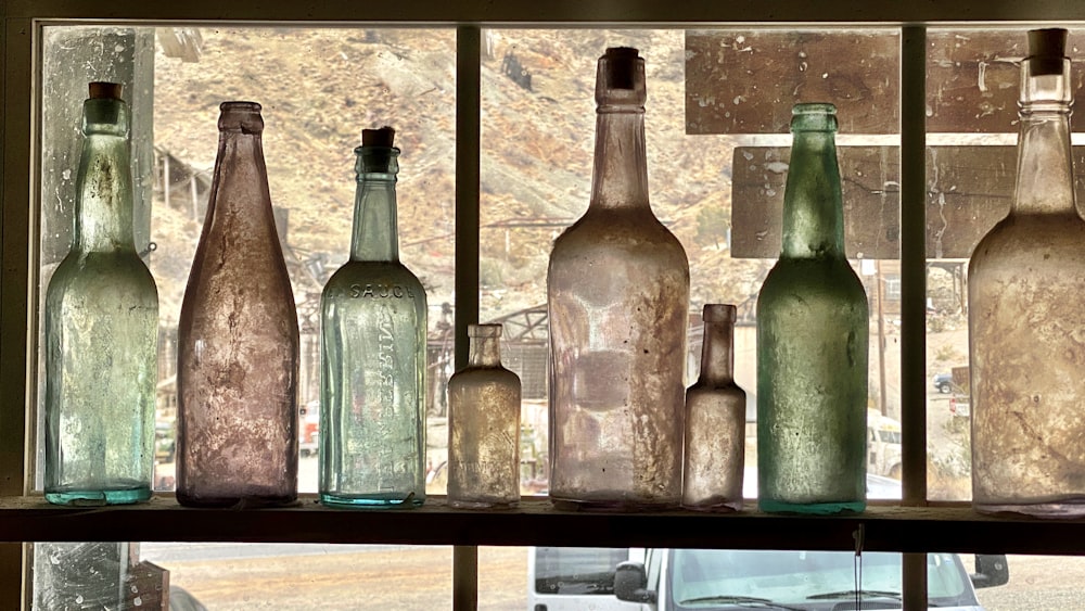 a bunch of bottles that are sitting on a window sill