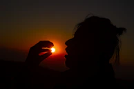 Sunset silhouette of a person holding an everythingie everythingie piece, symbolizing connection and creativity.