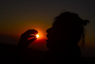Sunset silhouette of a person holding an everythingie everythingie piece, symbolizing connection and creativity.