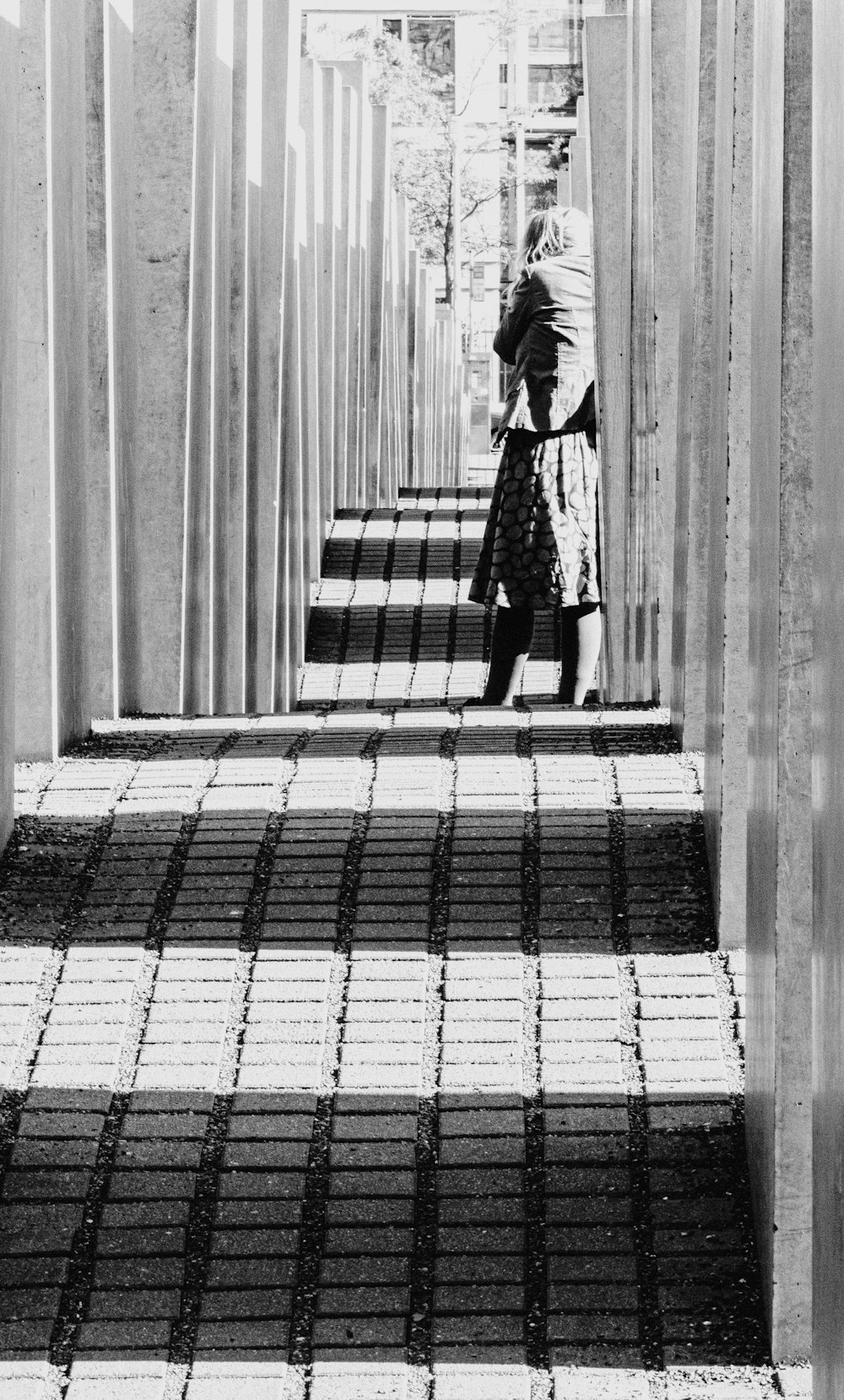 a black and white photo of a woman walking down a walkway
