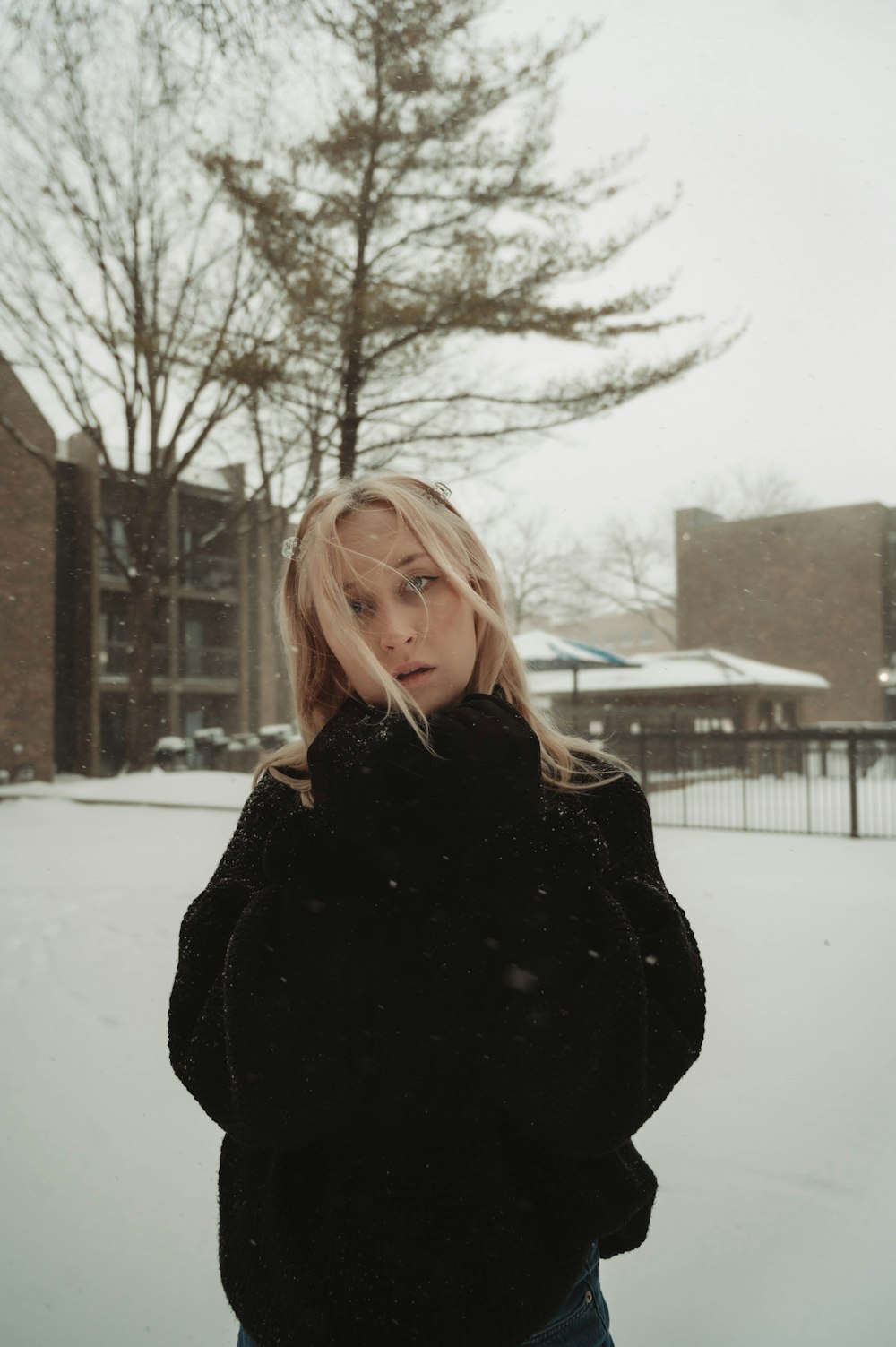a woman standing in the snow in front of a building