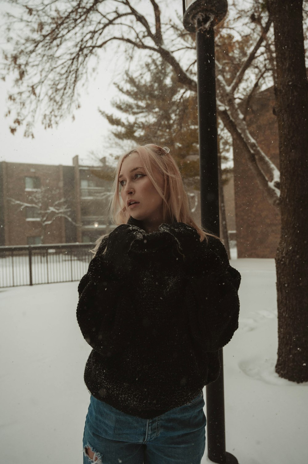 a woman standing next to a street light in the snow