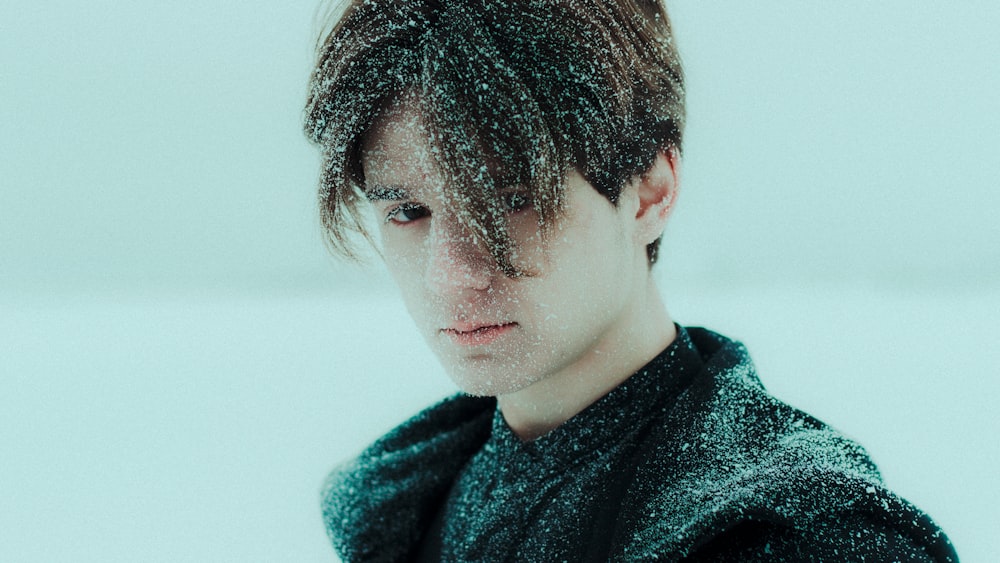 a man in a black coat with snow falling on him