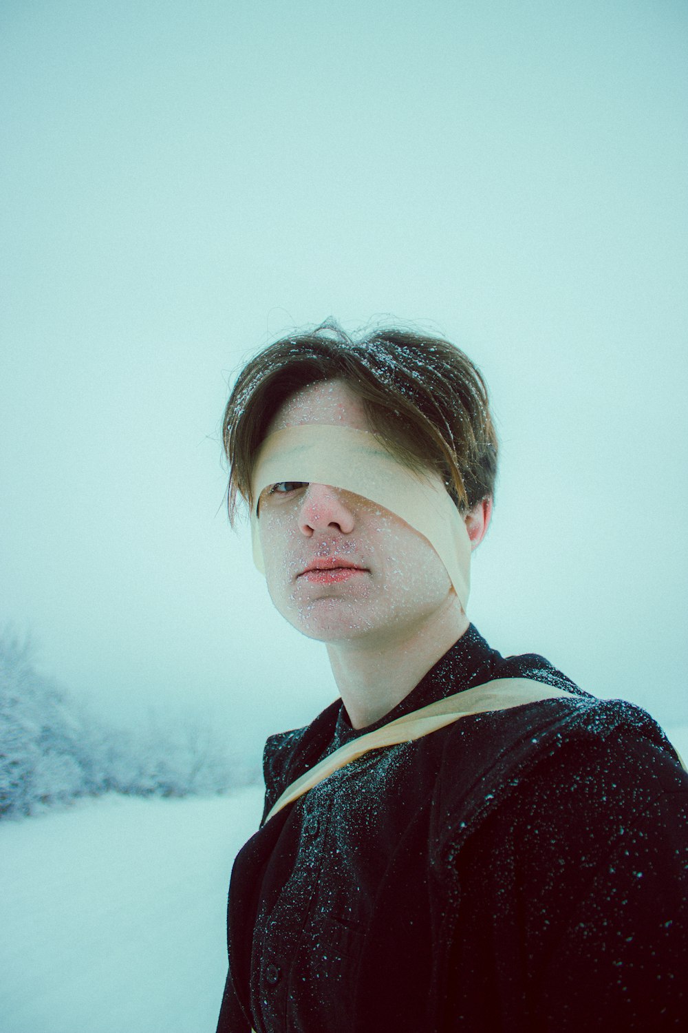 a man with a bandage on his face standing in the snow