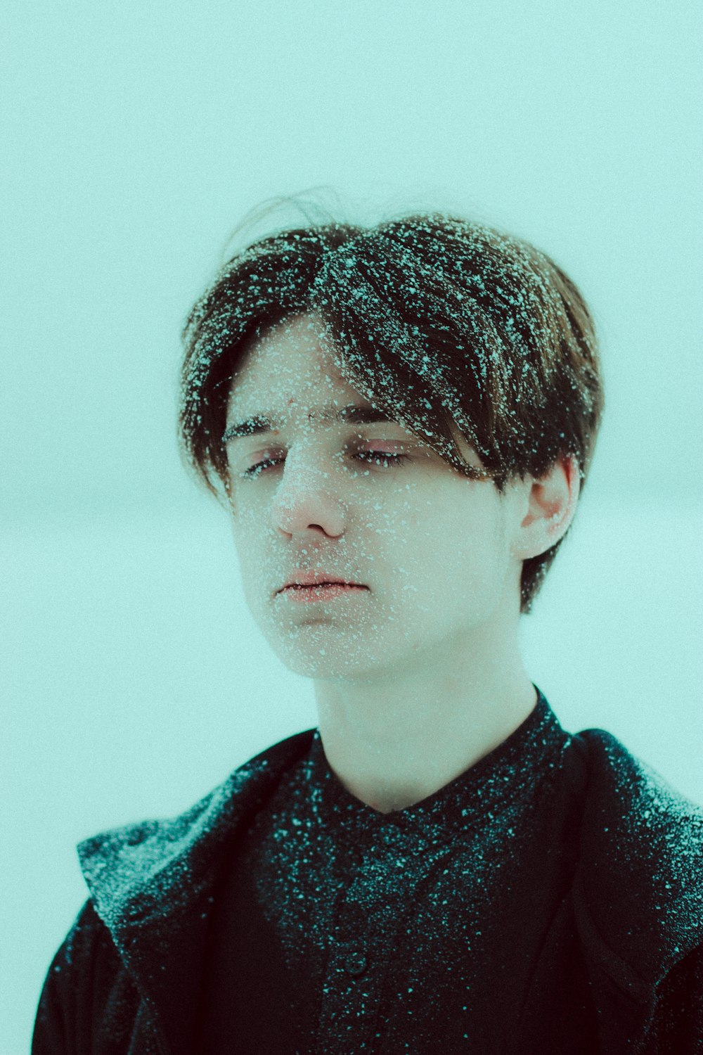 a young man standing in the snow with his eyes closed