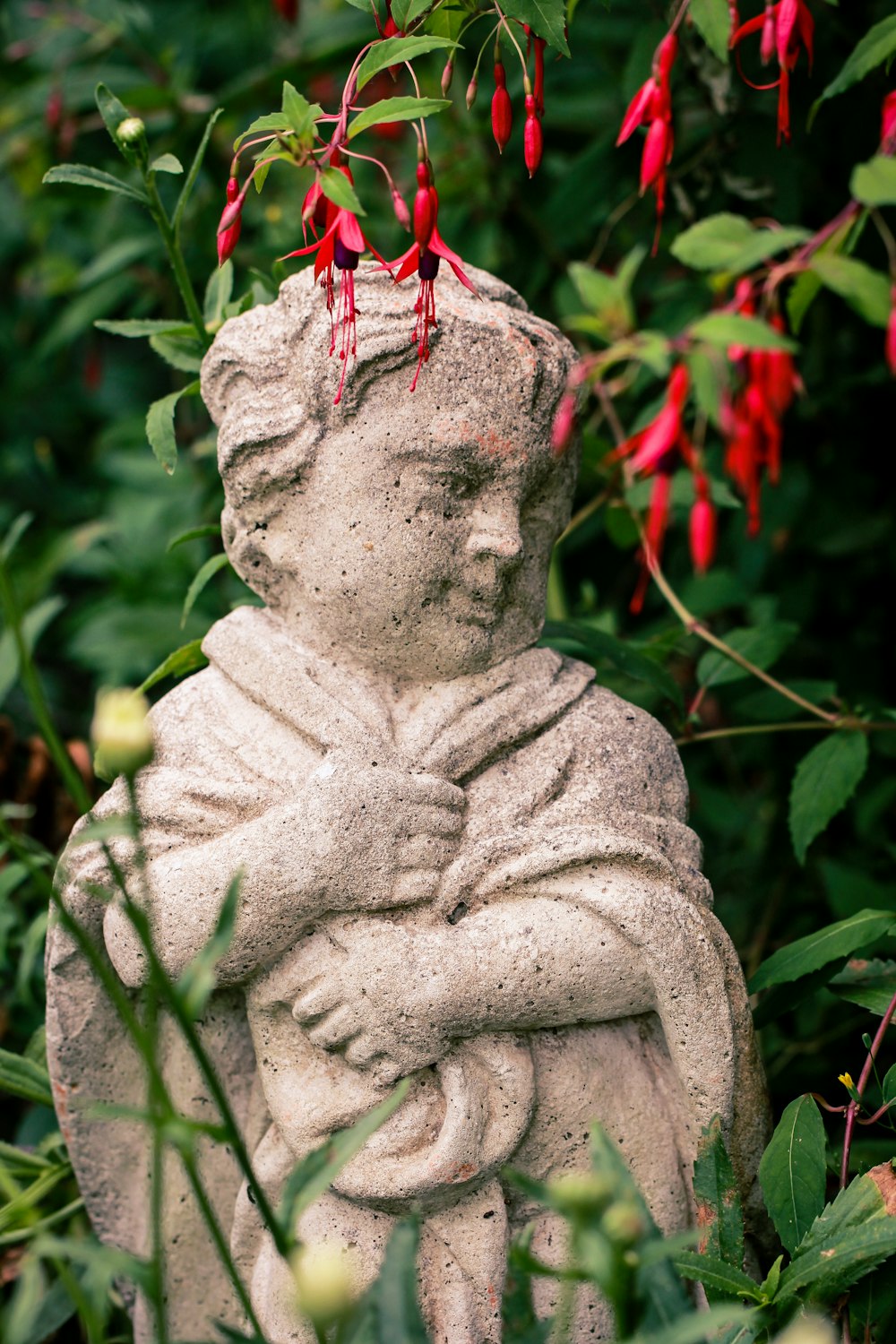 a statue of a person holding a child in a garden