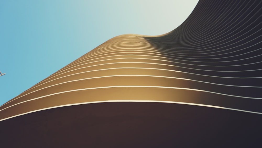 a plane flying over a tall building under a blue sky