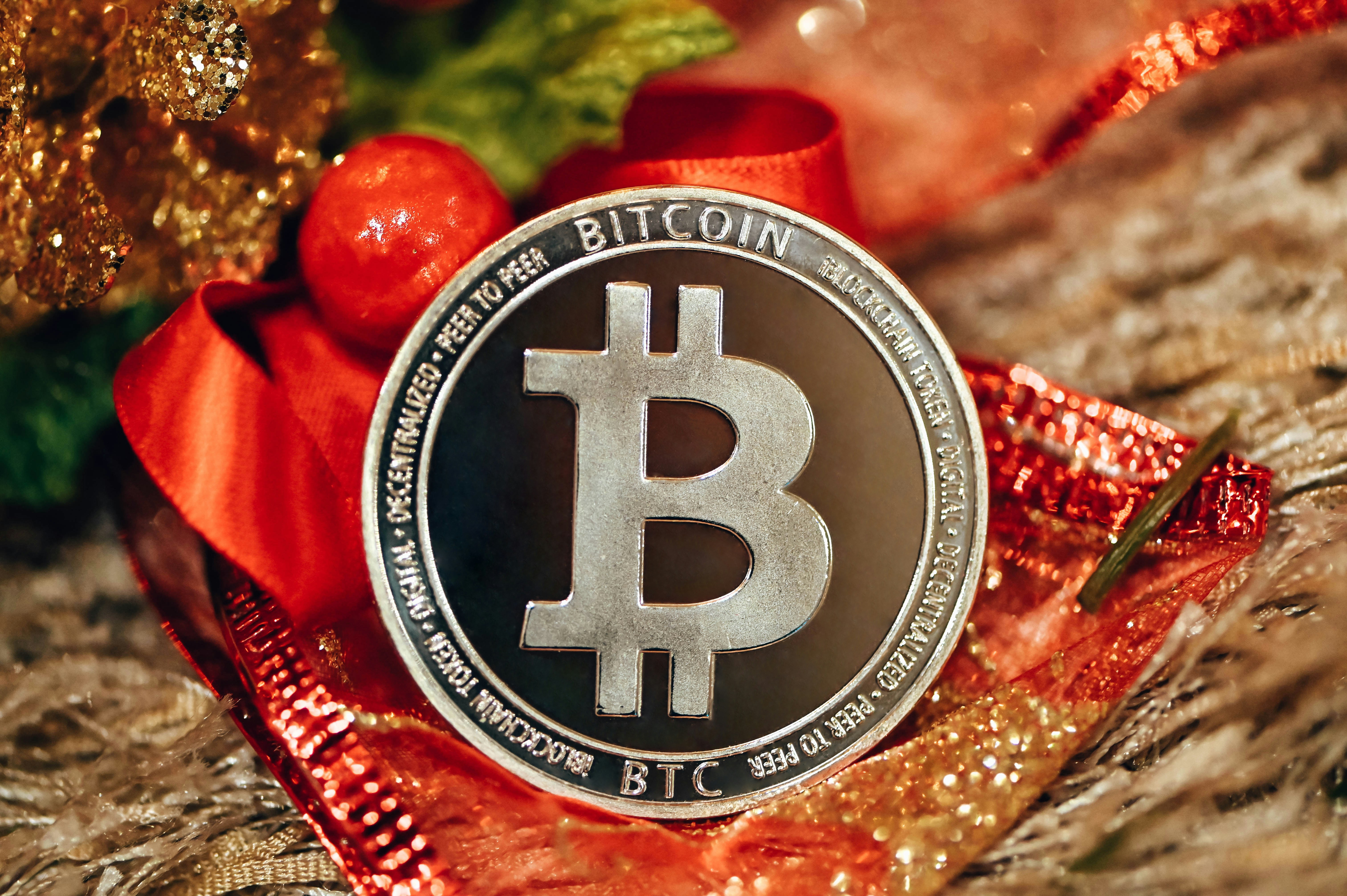 A silver Bitcoin stands on red fabric