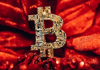 a golden bitcoin sitting on top of a red blanket