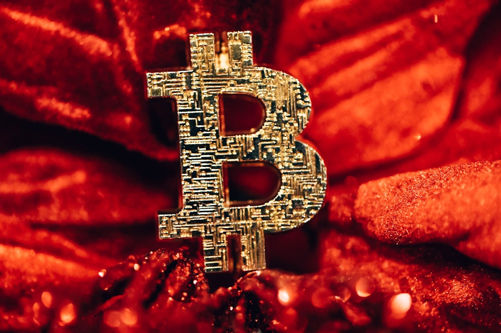 a golden bitcoin sitting on top of a red blanket