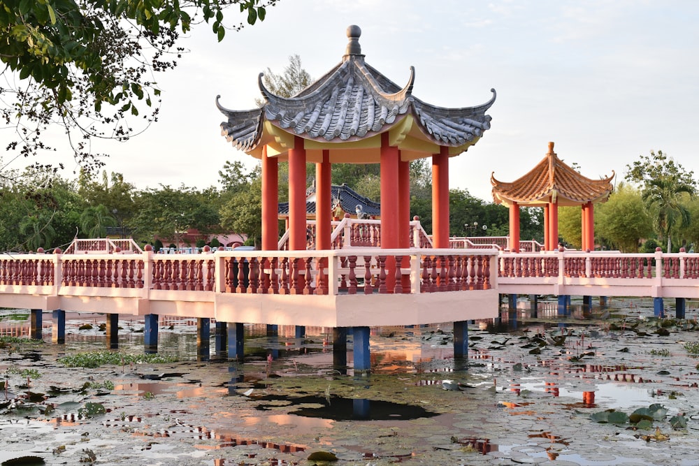 a bridge over a body of water with a pavilion in the background