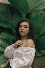 a woman standing in front of a green plant