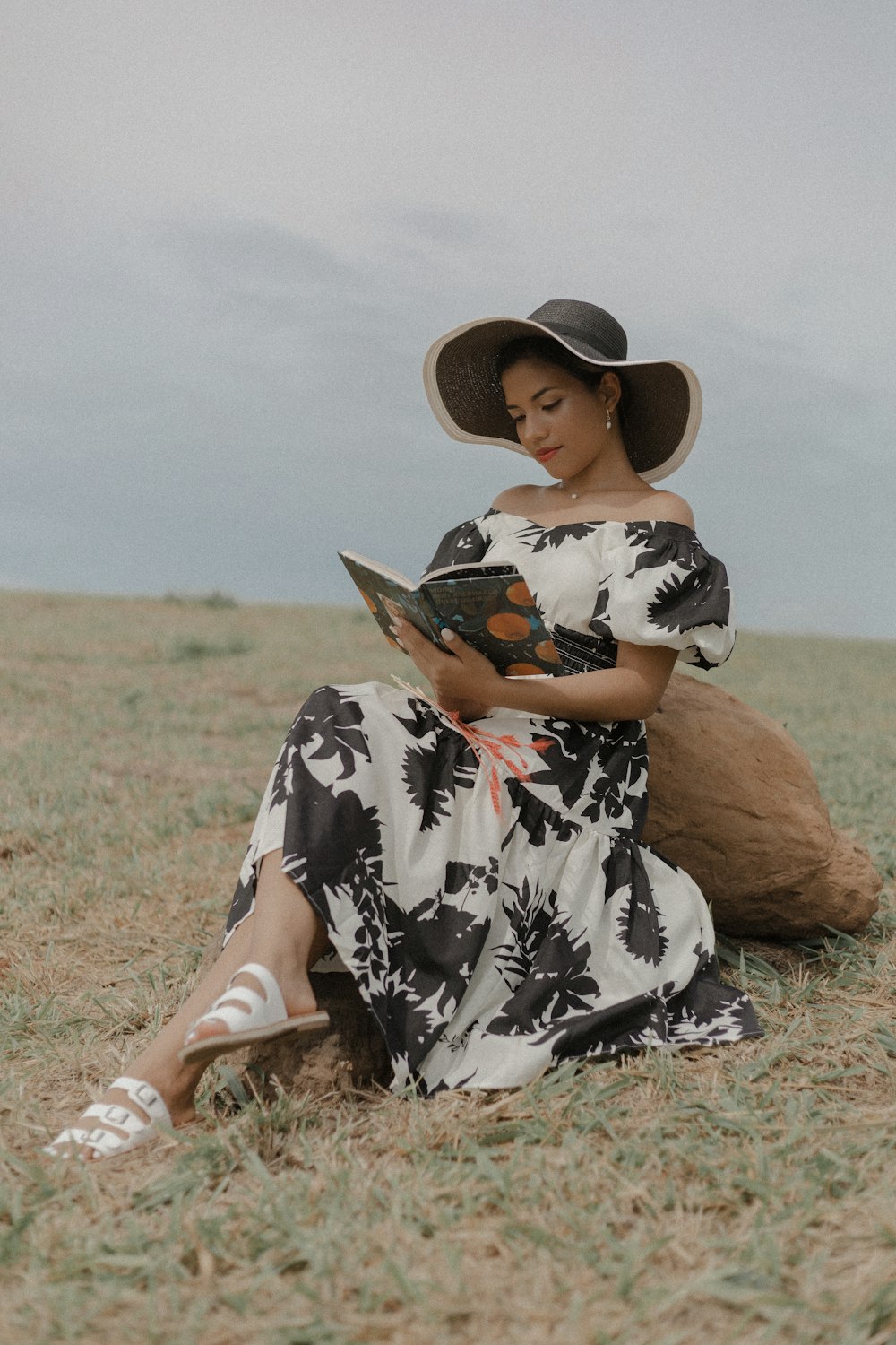 a woman sitting in a field reading a book