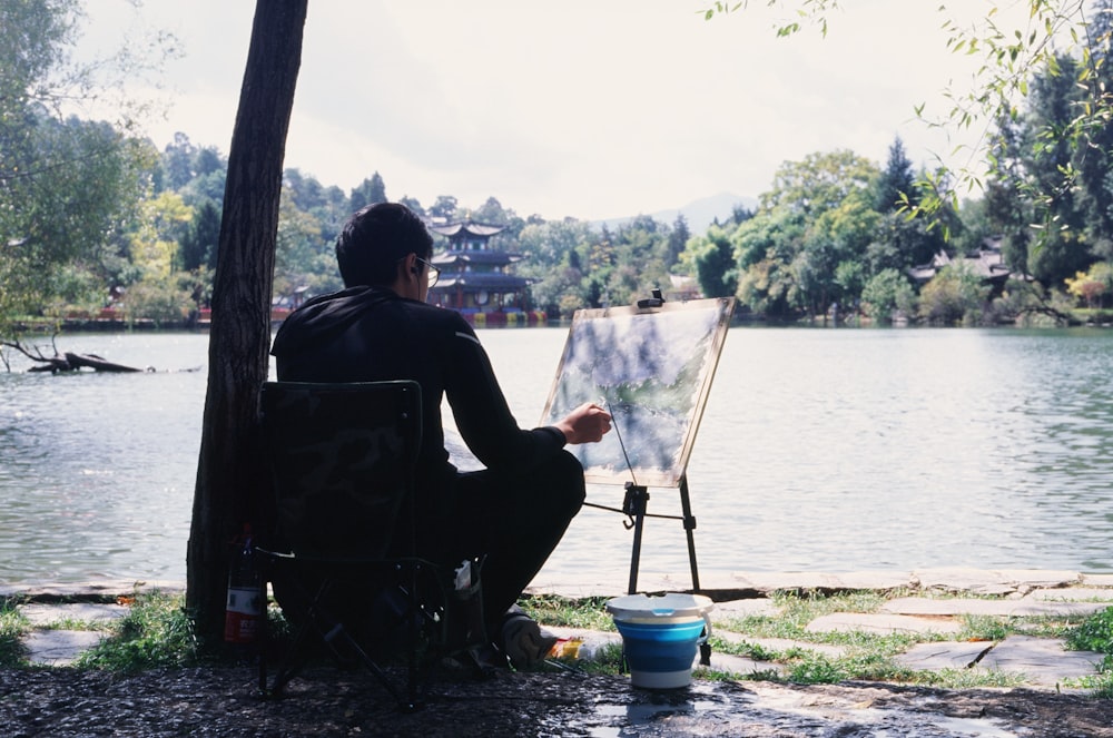 a man sitting in a chair next to a body of water