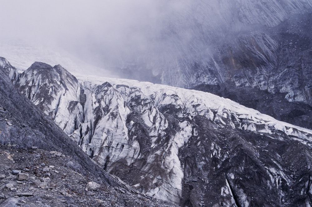 a mountain covered in snow and clouds on a cloudy day