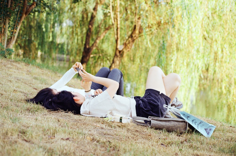 a woman laying on the ground next to a lake