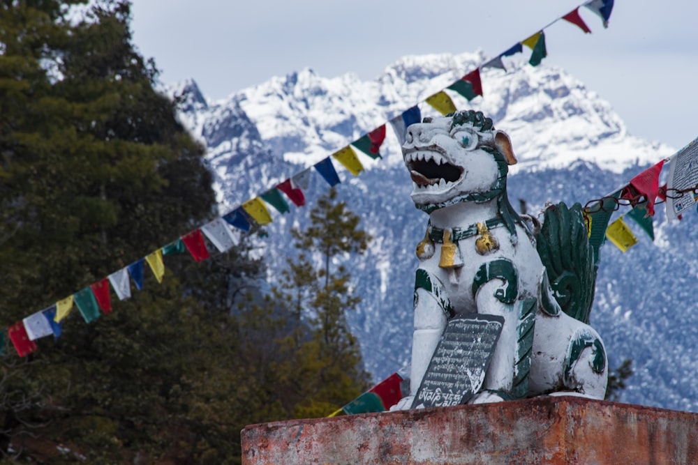eine Statue eines Hundes auf einem Podest mit einem Berg im Hintergrund