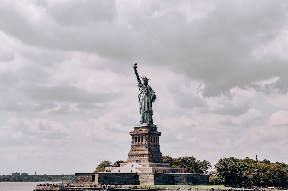 the statue of liberty stands in the middle of a body of water