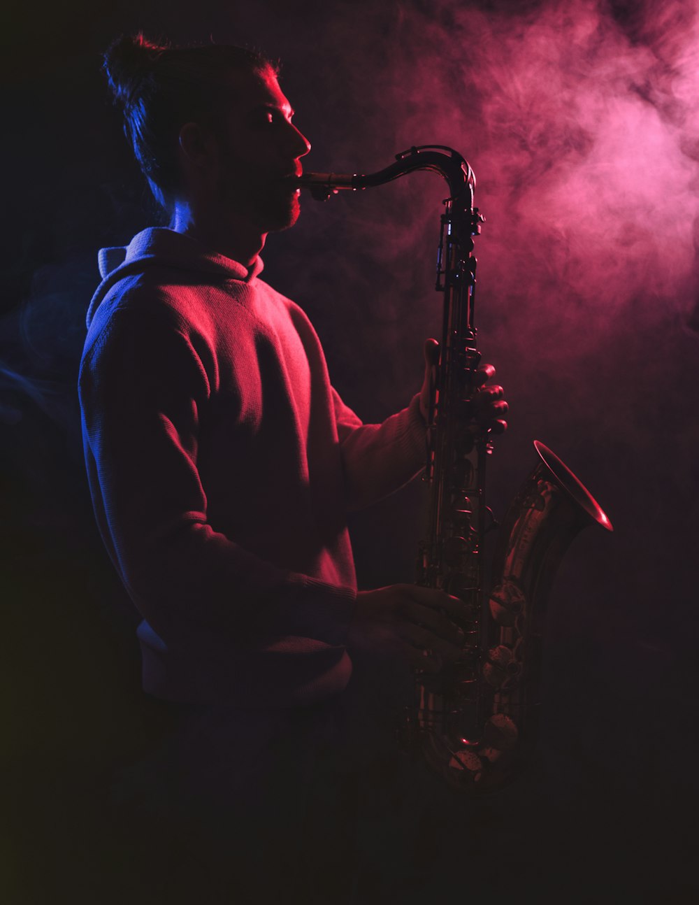 a man playing a saxophone in a dark room