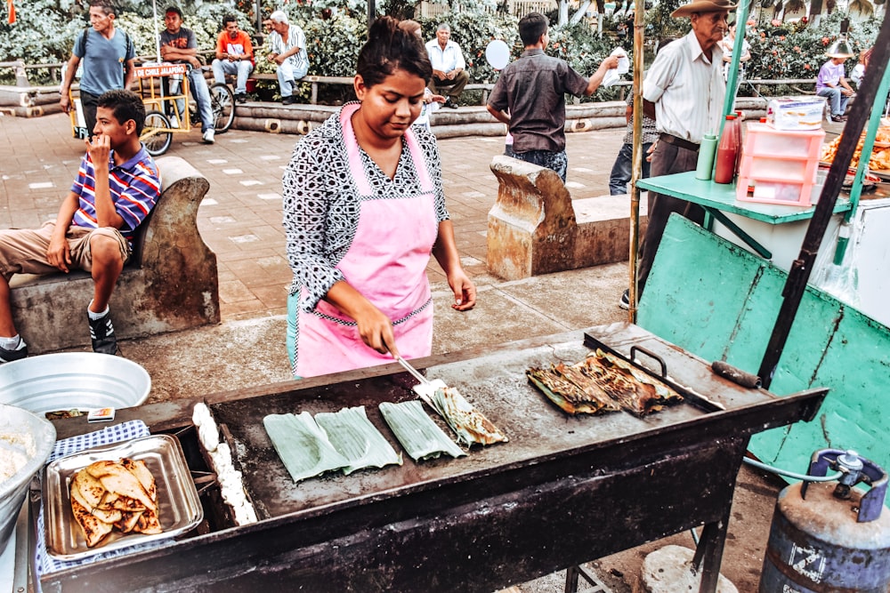 Una mujer cocinando comida en una parrilla al aire libre