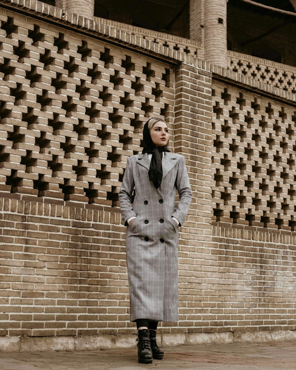 a woman standing in front of a brick wall