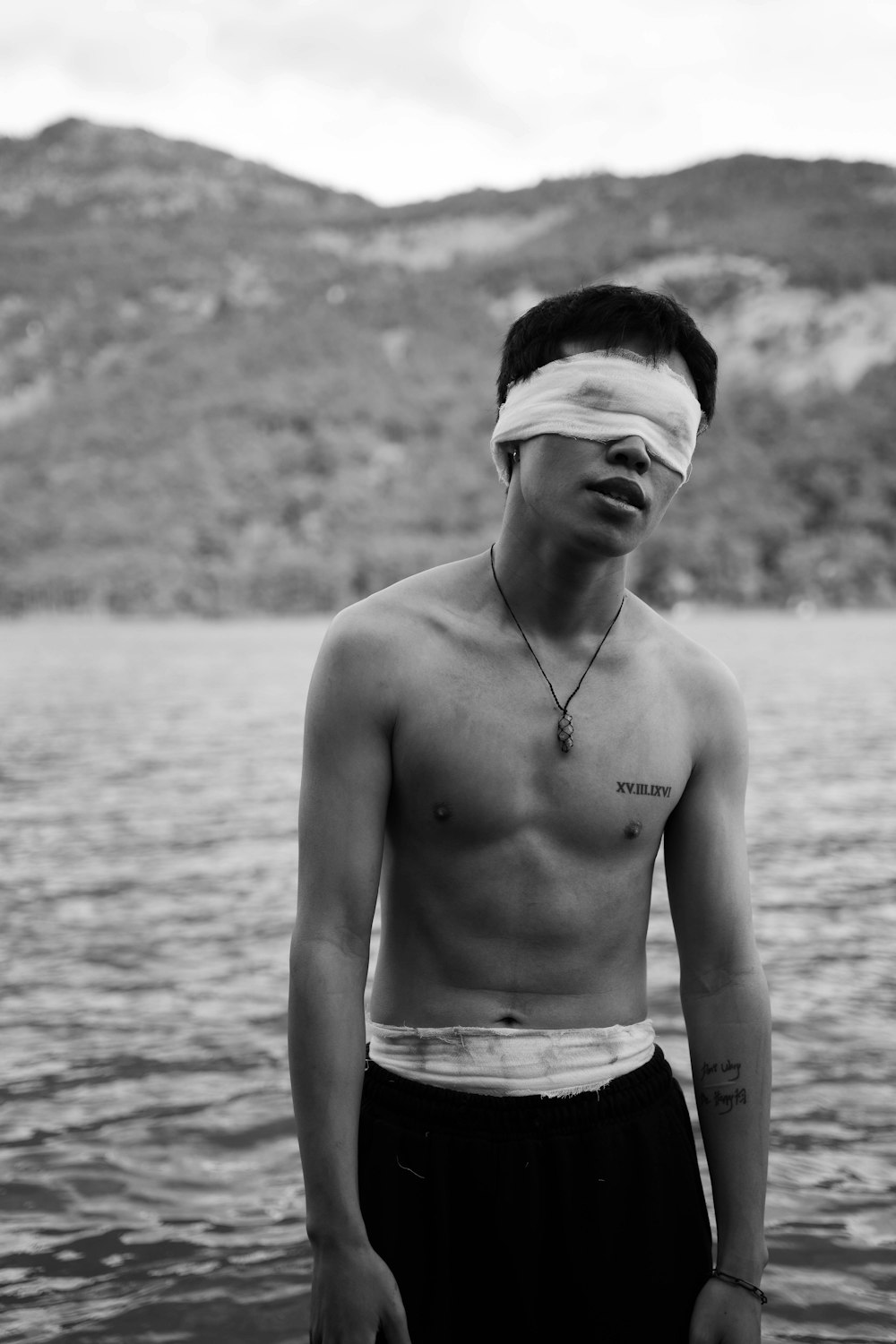 a shirtless man with a blindfold on his face