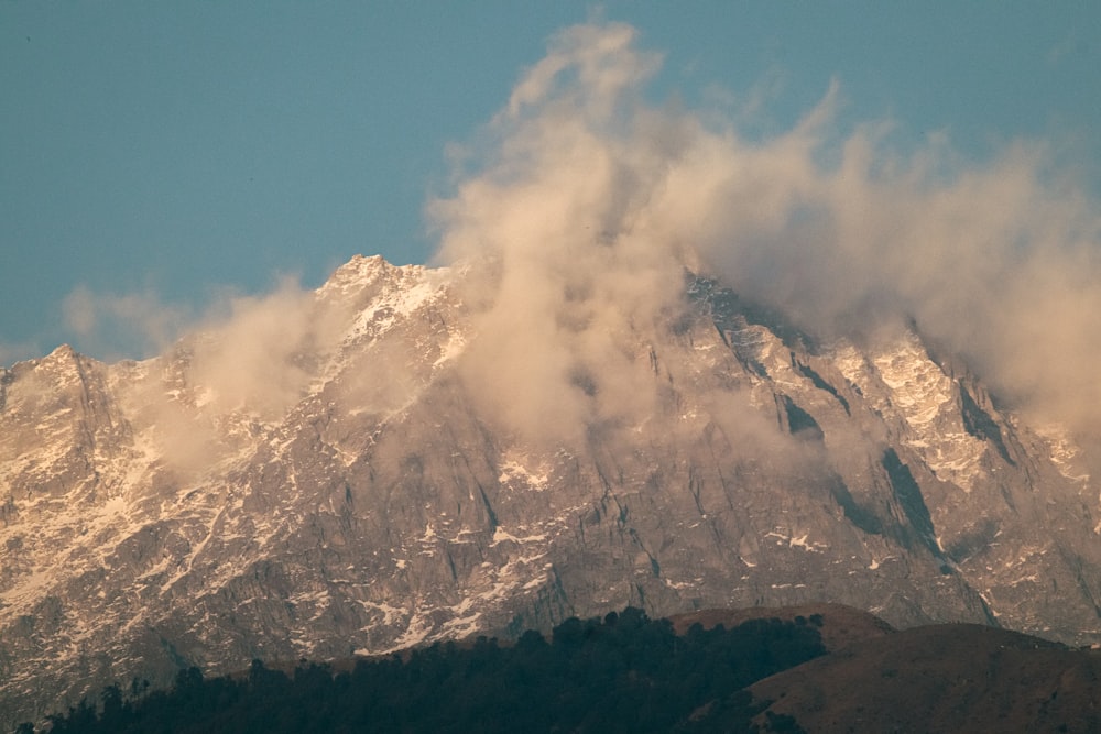 a large mountain covered in snow and clouds