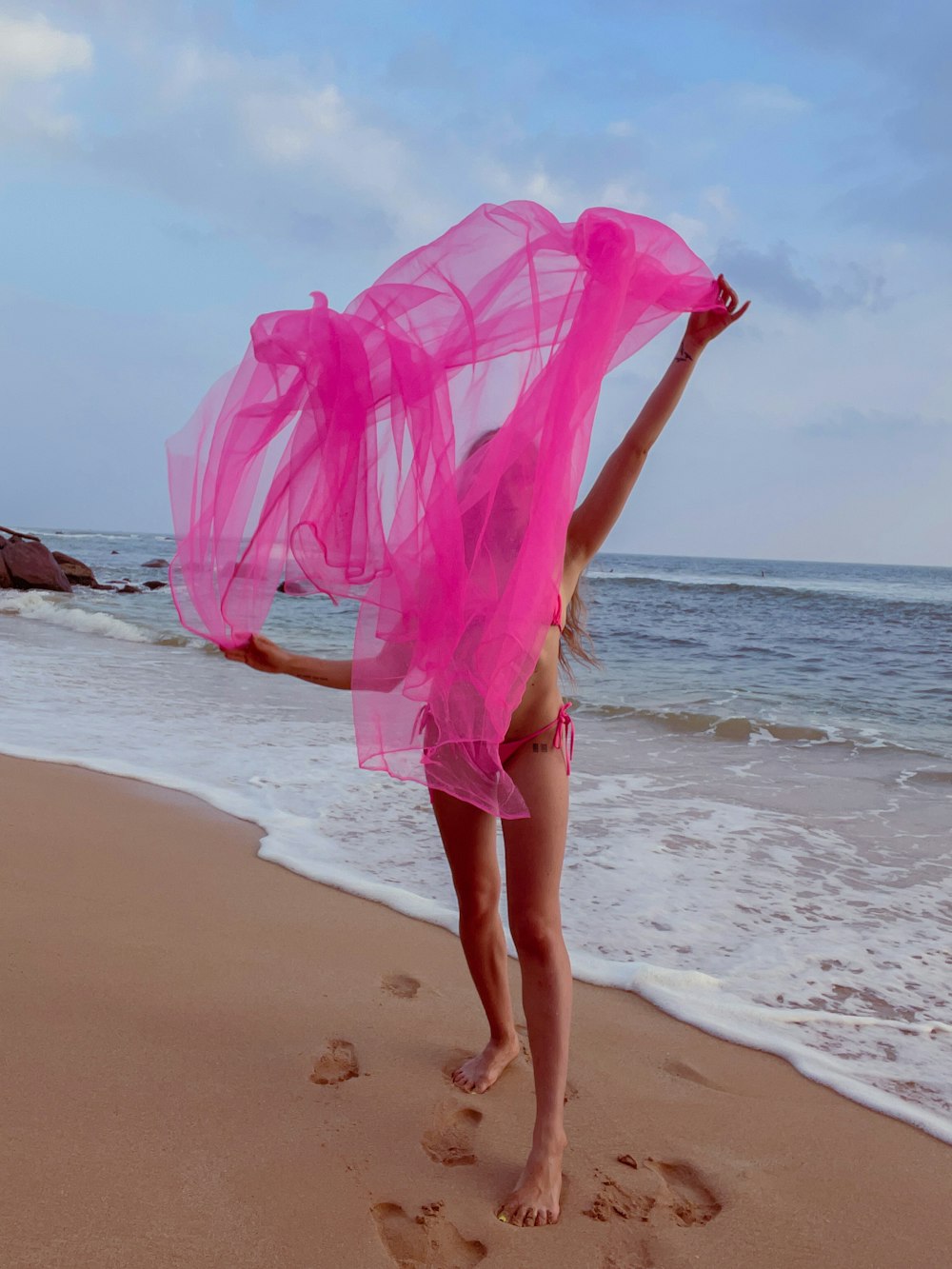 a young girl in a pink dress on the beach