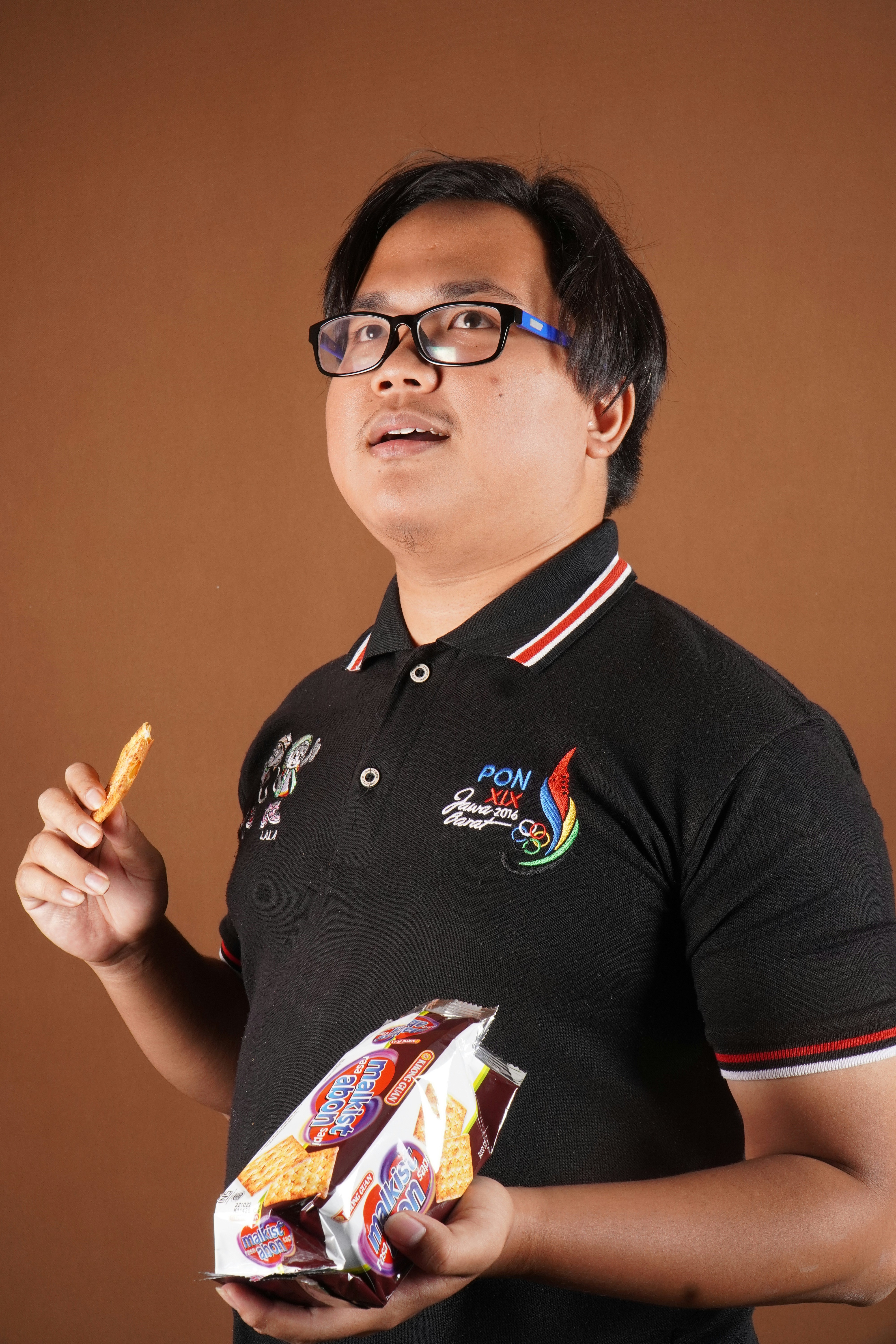 a man in a polo shirt holding a bag of chips