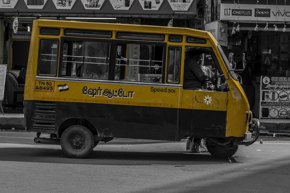 a yellow and black bus driving down a street