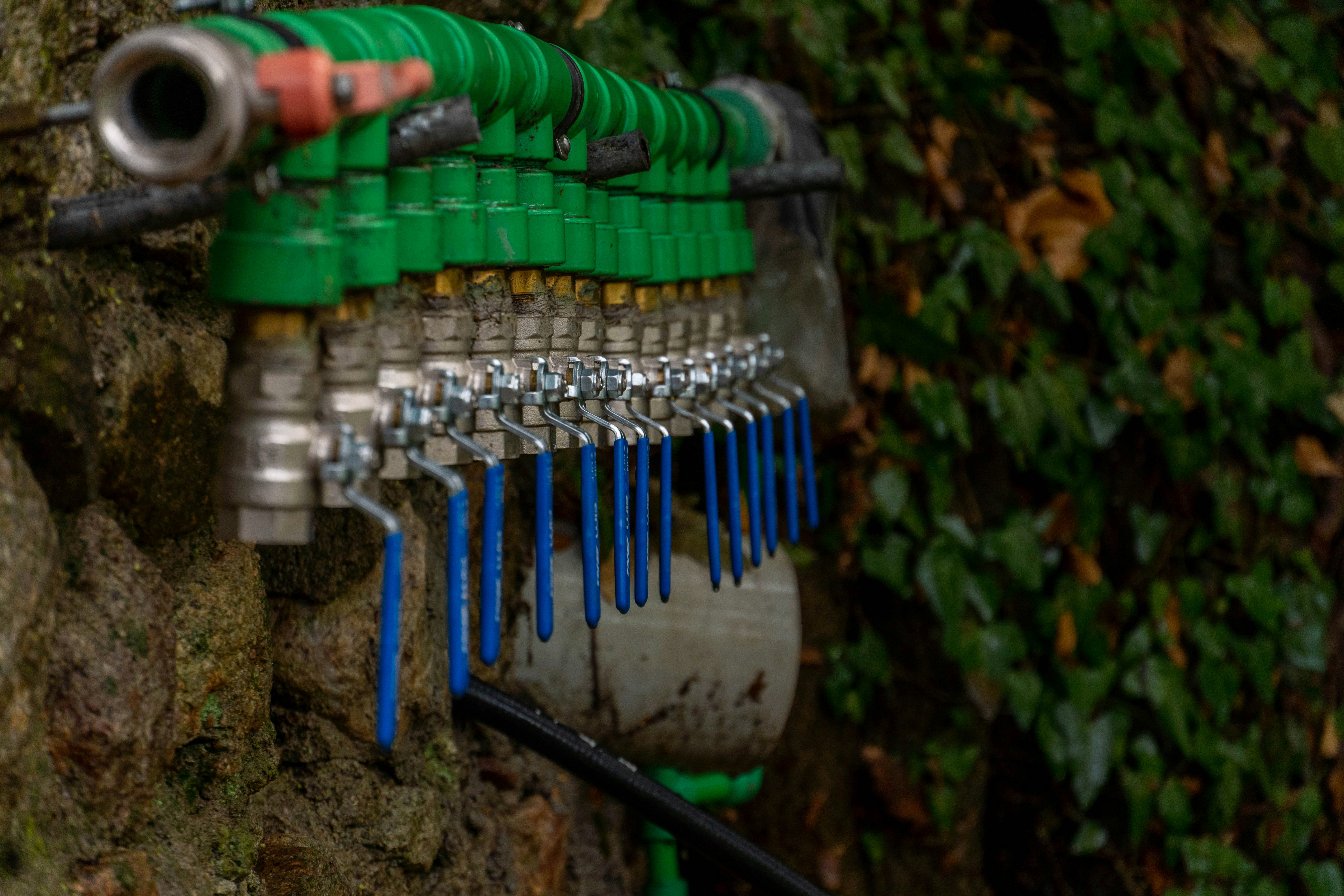 a bunch of green and blue hoses attached to a wall