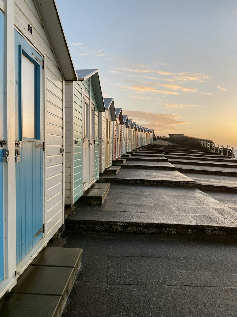 a row of white and blue beach huts next to the ocean