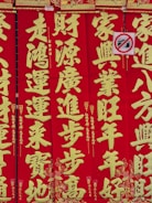 Bright red vertical banners display large gold Chinese characters with intricate decorative patterns. A small no-photography sign is partially visible, featuring a crossed-out camera icon.