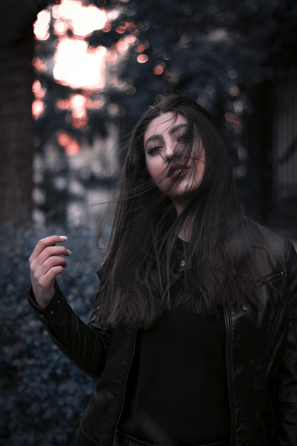 a woman with long hair and makeup holding a cigarette