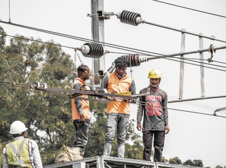 a group of men standing on top of a power line