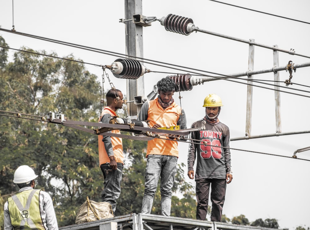 a group of men standing on top of a power line