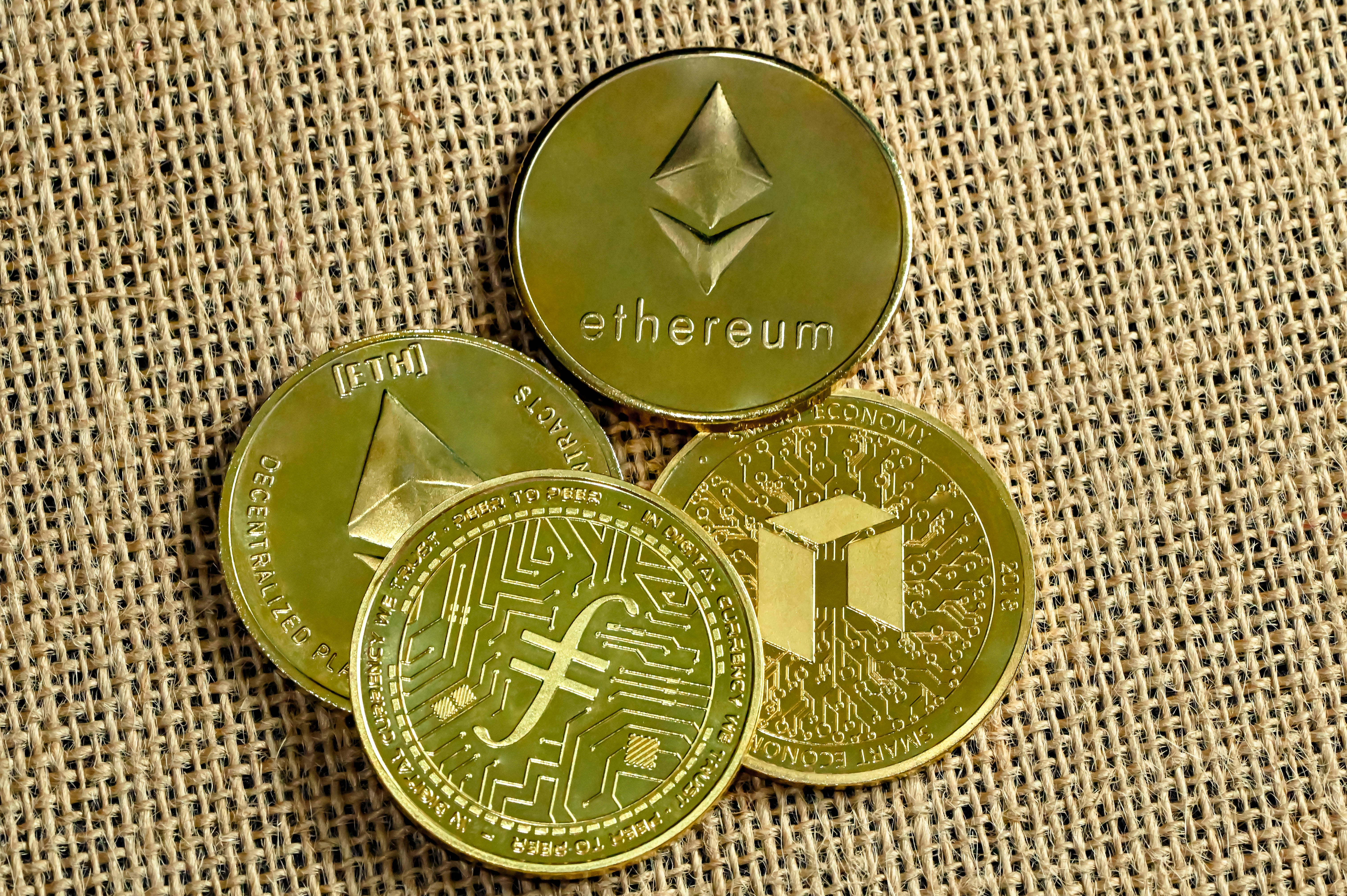 Ethereum coins, Filecoin and NEO coin on a woven background
