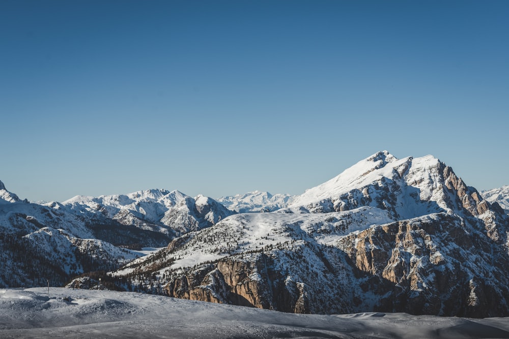 a mountain range covered in snow under a blue sky